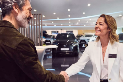 Man and woman shaking hands in a car showroom.
