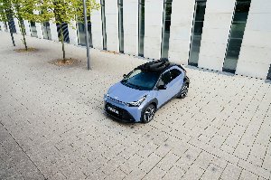 Four compact cars parked in front of a modern building.