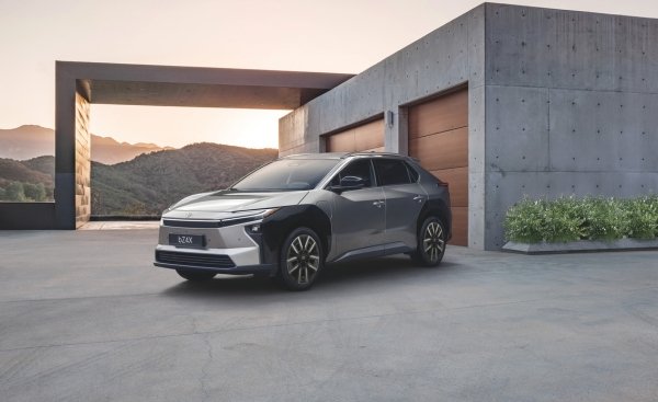 A silver SUV parked near a modern concrete house.