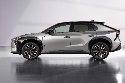 Side view of a grey SUV with black accents on a reflective floor.