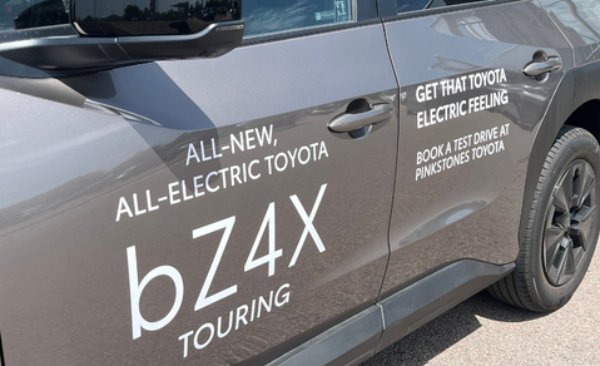 Side view of a grey Toyota bZ4X Touring with promotional text on its door.