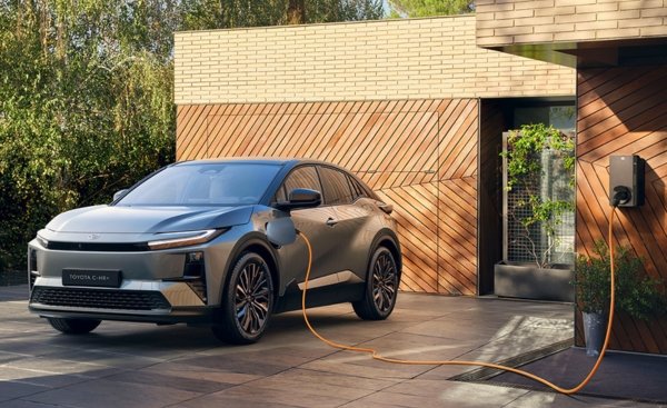 Electric SUV plugged into a wall-mounted charging station outside a modern building.