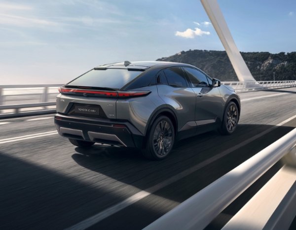 A grey car driving on a road bridge, rear view.