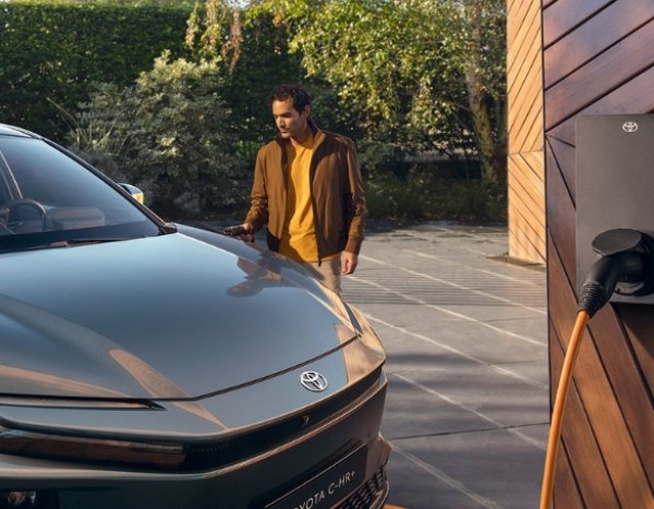 A man approaches a Toyota C-HR car parked near a charging station.