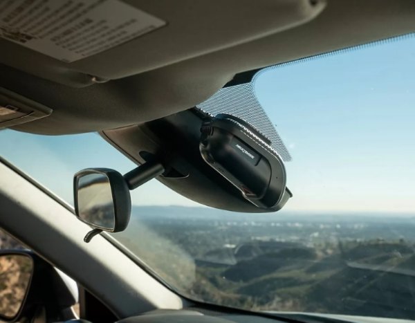 Car dashboard with a radar detector mounted below the rear-view mirror.