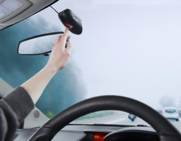 Hand adjusting a car's dashcam.