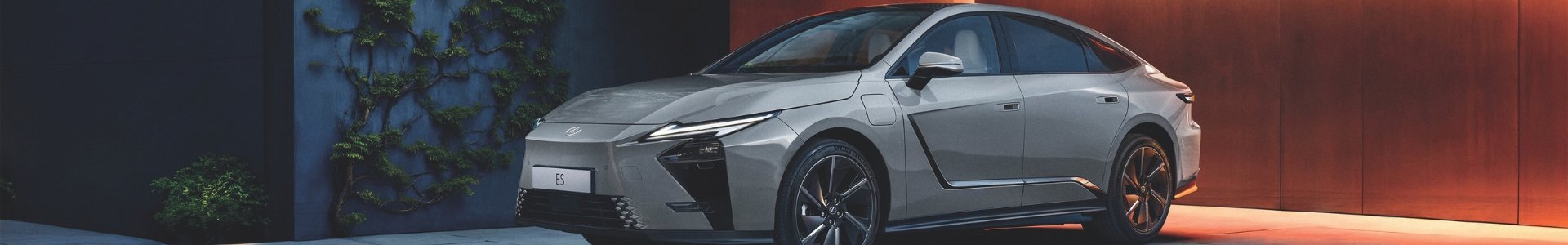 Sleek, modern car parked beside a wall with climbing plants.
