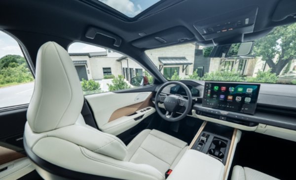 Modern car interior with touchscreen display and light upholstery viewed from the driver's seat.