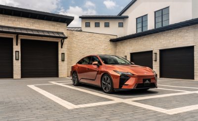 Orange car parked in front of a modern house with garages.