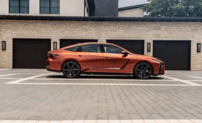 Orange modern car parked in front of a house with three garage doors.