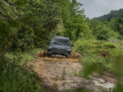 SUV driving through muddy terrain in a forest.