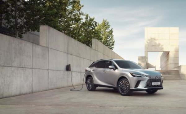 Silver car parked near a charging station beside a concrete wall.