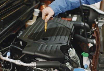 Mechanic checking car engine oil with dipstick.
