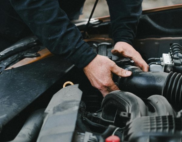 Mechanic working on a car engine with both hands.