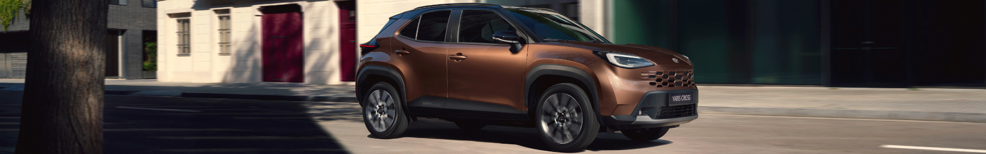 Bronze-coloured compact SUV driving on a city street.