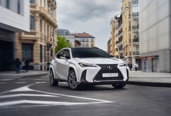 White Lexus UX driving on an urban street.