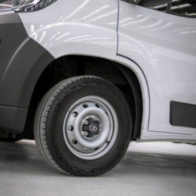 Close-up of a van's front wheel with a white and black hubcap design.