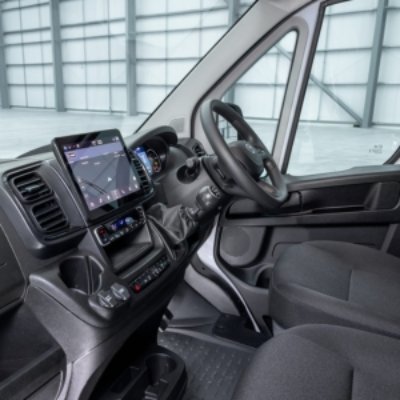 Van interior with steering wheel, touchscreen navigation, and black seats.