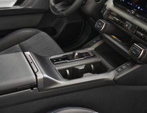 Close-up of a car's centre console with gear selector and cup holders.