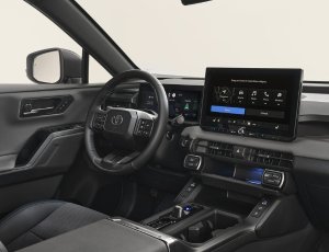 Car interior featuring a steering wheel and large central touchscreen display.
