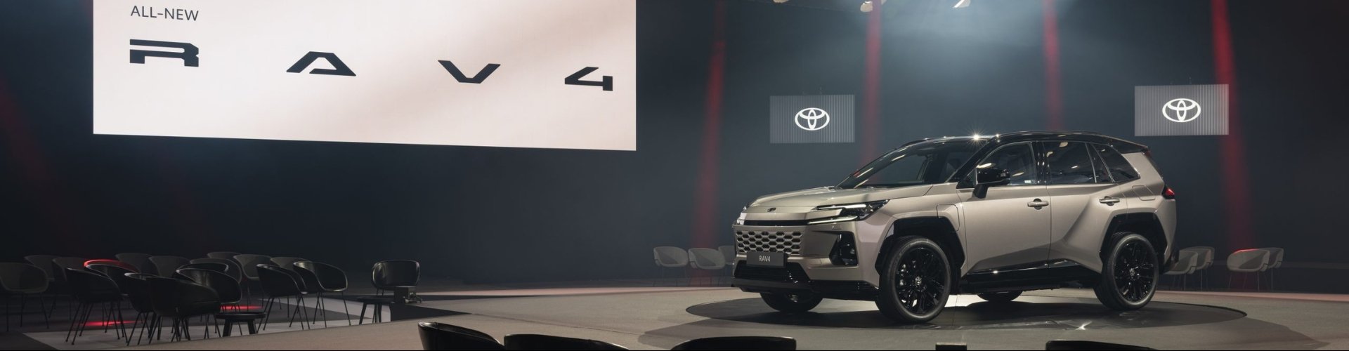 New Toyota RAV4 SUV on display in an indoor venue with chairs.