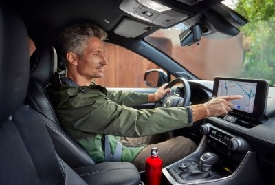A man driving a car while using a touchscreen GPS.