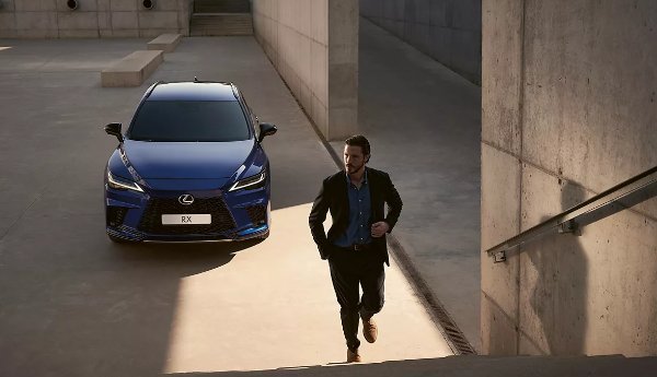 Man walking up steps near a blue Lexus RX parked below.