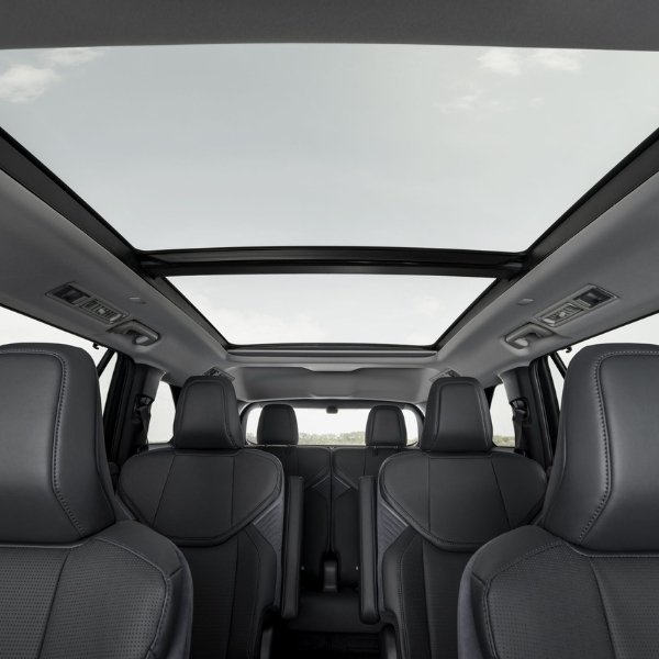 View of a car's interior with a panoramic sunroof and five black leather seats.