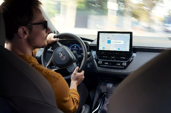 Person driving a car with a navigation system displayed on the dashboard screen.