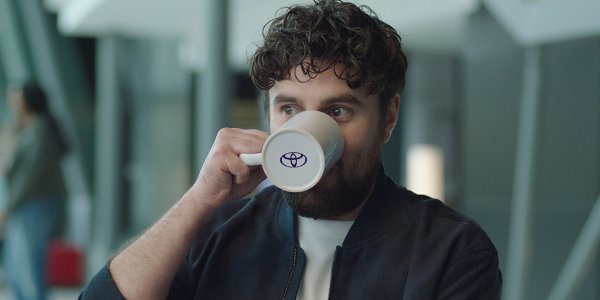 Man drinking from a mug with a Toyota logo.