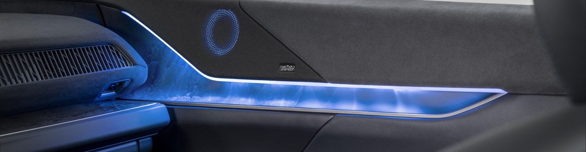 Car interior door panel with speaker and blue ambient lighting.