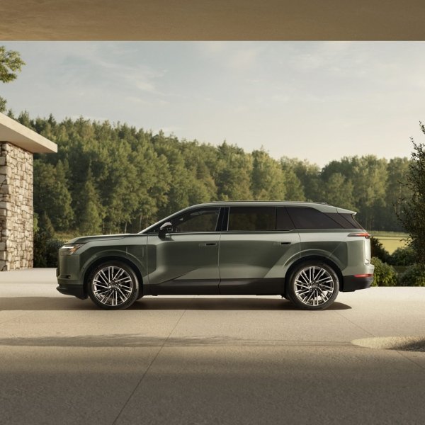 Side view of a green SUV parked on a driveway with trees in the background.