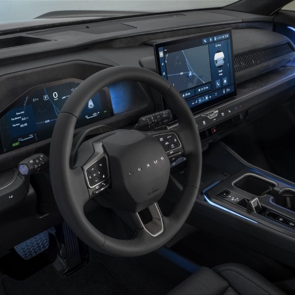 Interior view of a vehicle dashboard with steering wheel and digital display screens.