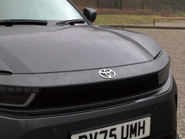 Close-up of a black Toyota car's front with raindrops on the bonnet.