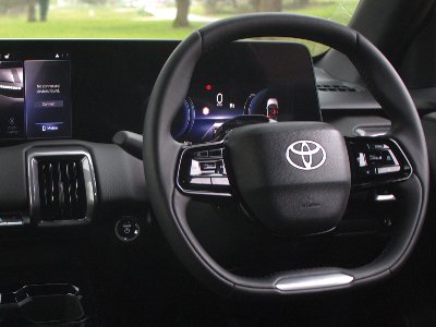 Close-up of a car's steering wheel and digital dashboard displays.