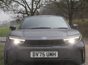 Front view of a grey Toyota car with headlights on and licence plate DV75 UMH.