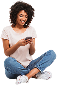 Woman sitting cross-legged, smiling at her phone.
