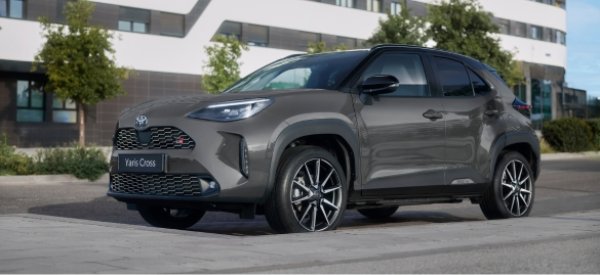 Grey Toyota Yaris Cross car parked on pavement, side and front view.