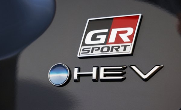 Close-up of a GR Sport badge and HEV logo on a grey vehicle.