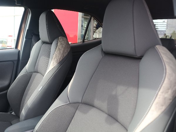 Close-up of two front car seats with grey upholstery and stitching detail.