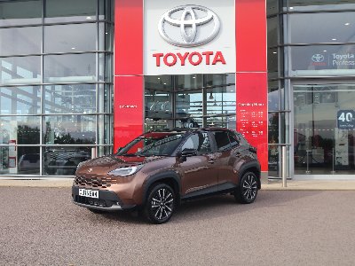 Brown Toyota car parked in front of a Toyota dealership.